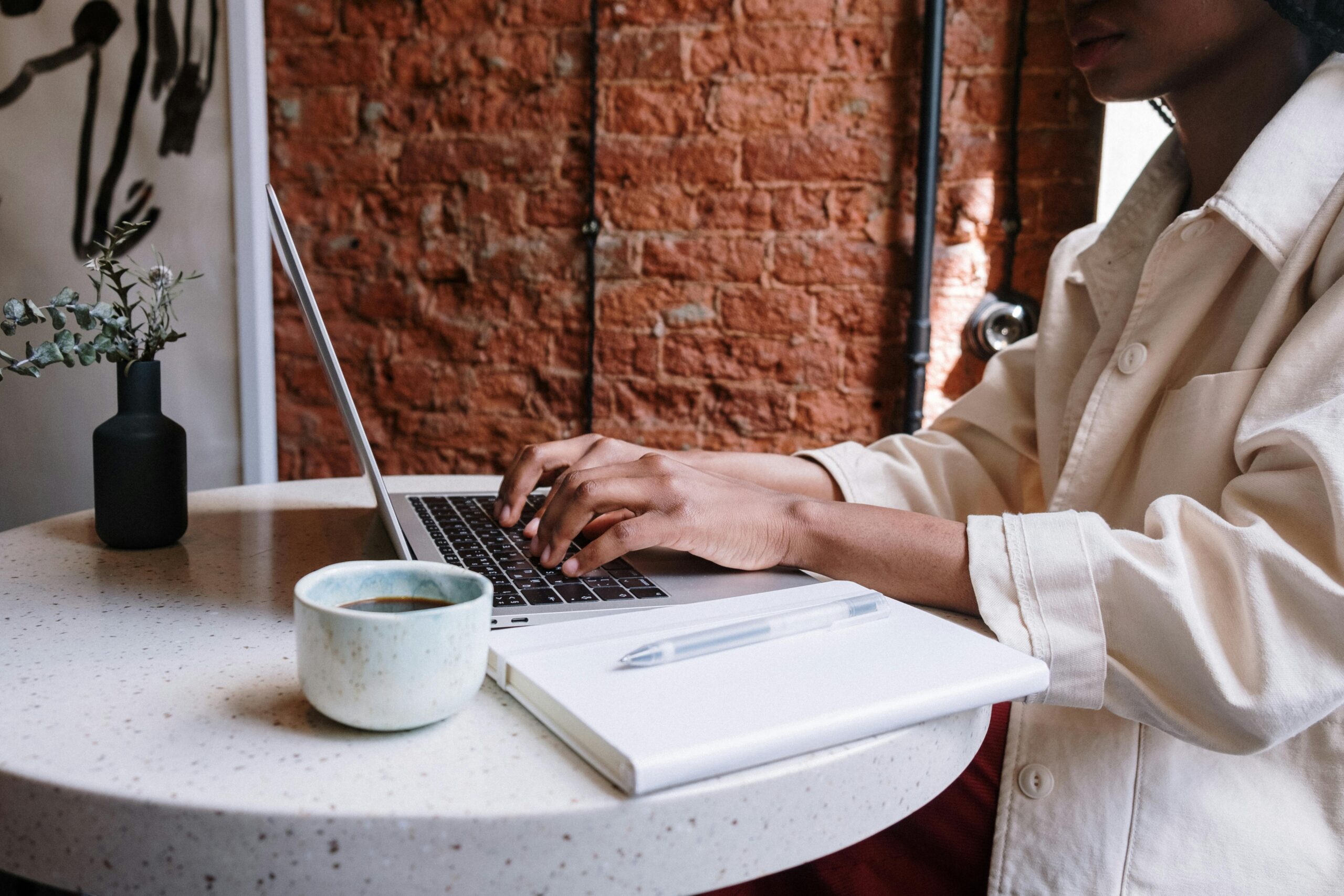 Woman working on a laptop with coffee in a cozy café, highlighting a productive and modern vibe.